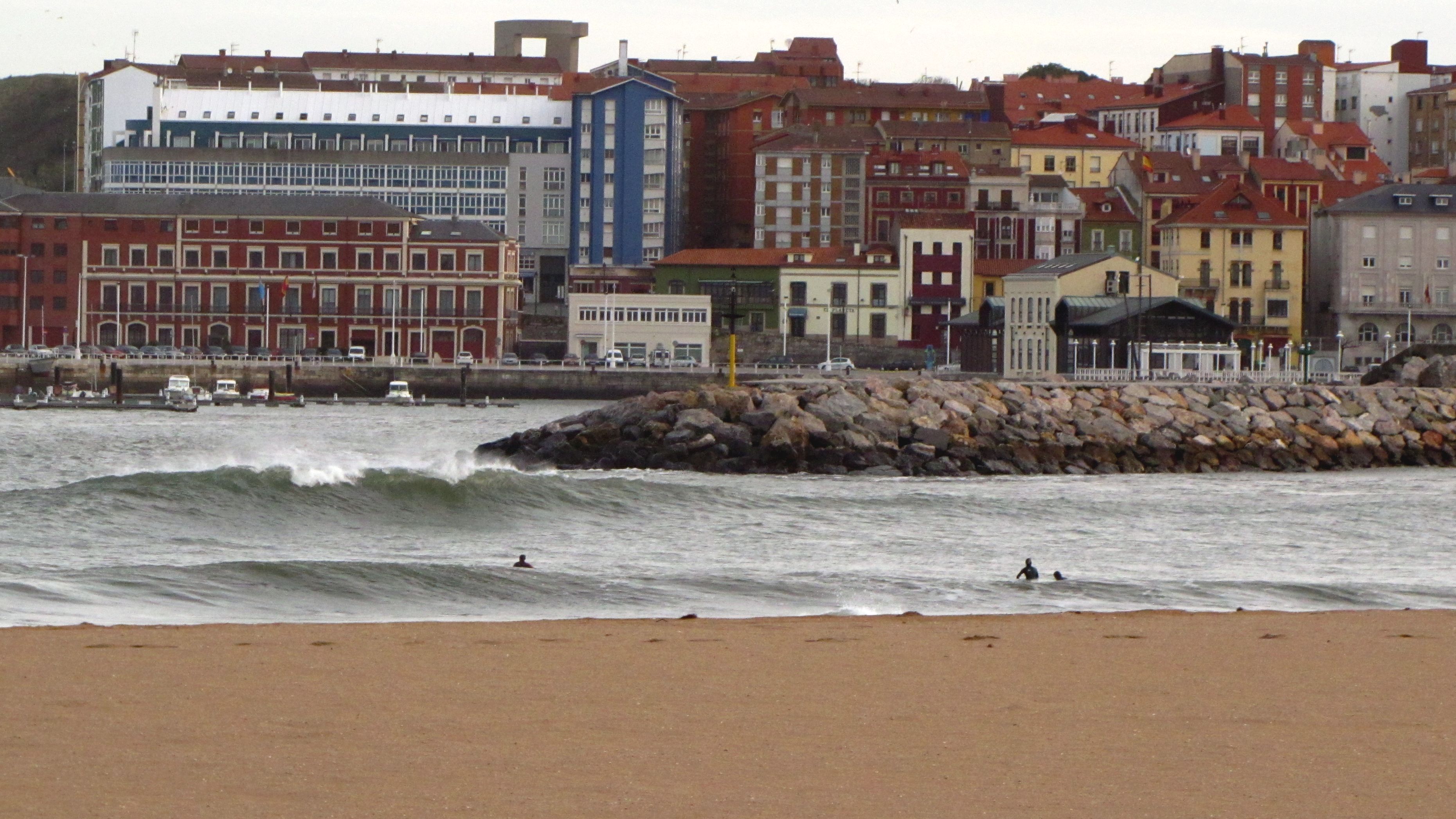 Vista del oleaje en la Playa de Poniente, con los edificios del muelle al fondo.